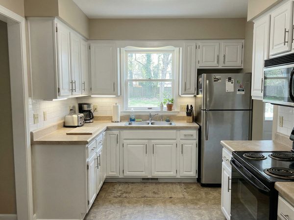 Kitchen with bright white painted cabinets and modern appliances after refinishing