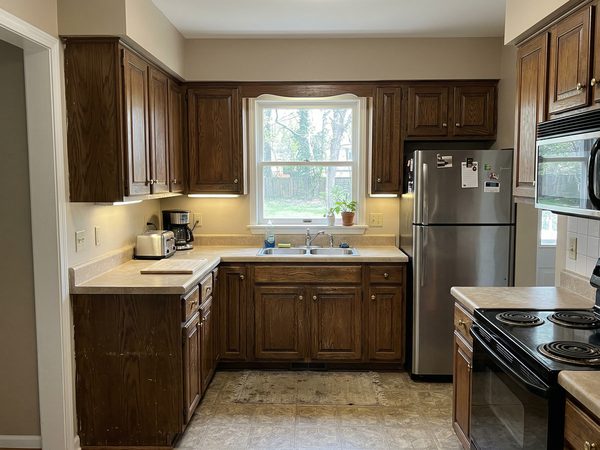 Kitchen with dated dark wooden cabinets before refinishing